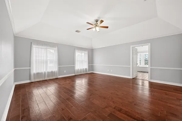 a view of an empty room with wooden floor and window