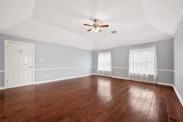 a view of empty room with wooden floor and fan