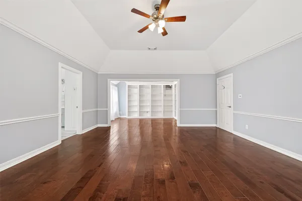 an empty room with wooden floor fan and windows