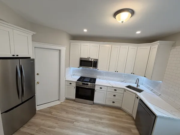 a kitchen with granite countertop white cabinets and stainless steel appliances