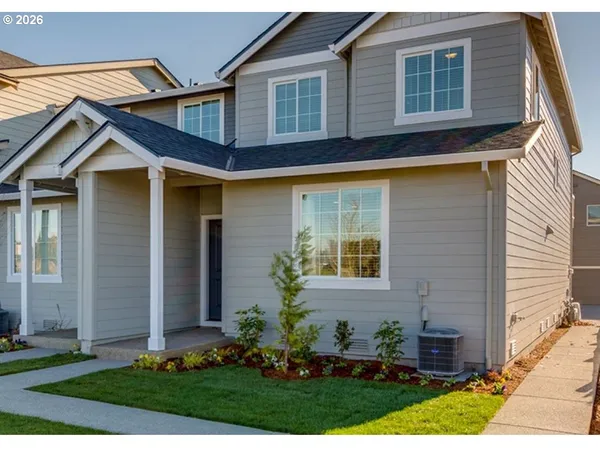 a view of a house with small yard plants and large tree