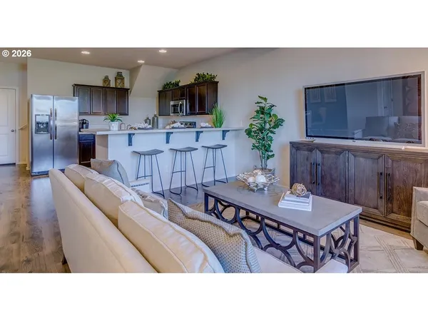 a living room with furniture a wooden floor and kitchen view