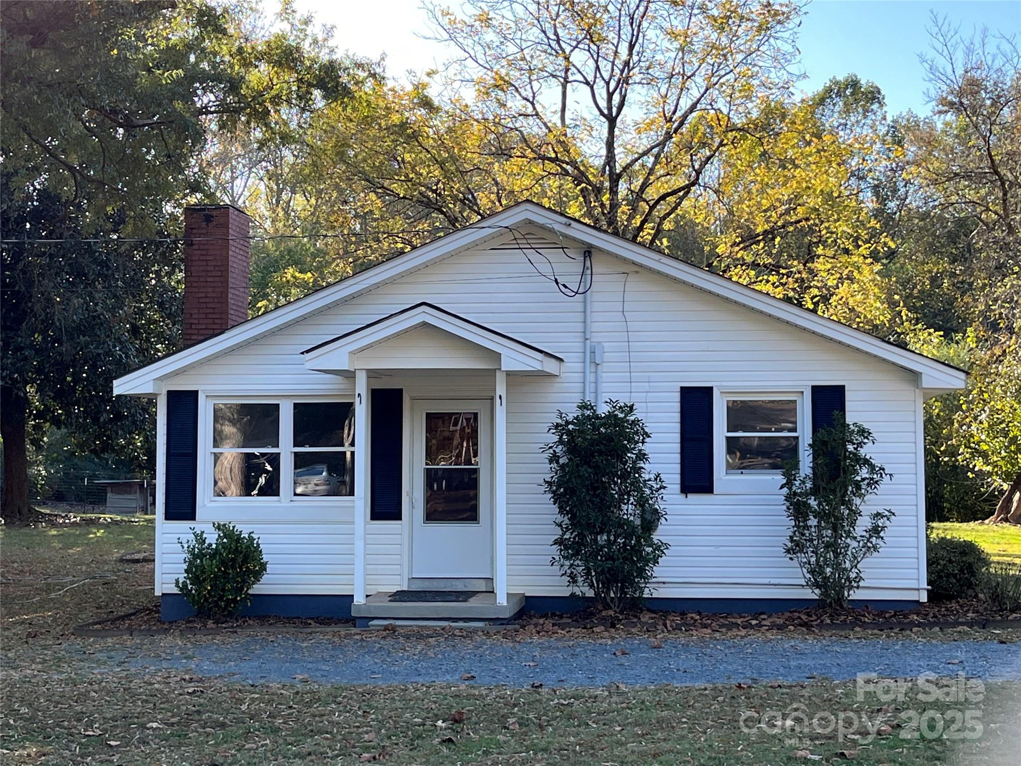 a front view of house with yard and trees in the background