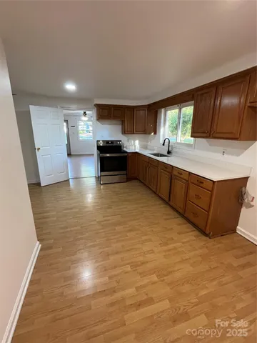 a large kitchen with stainless steel appliances a large counter top a stove and a wooden floors