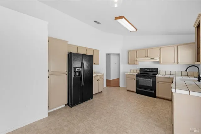 a kitchen with granite countertop a refrigerator and a stove top oven