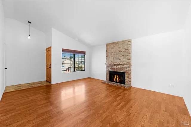 a view of empty room with wooden floor and fireplace