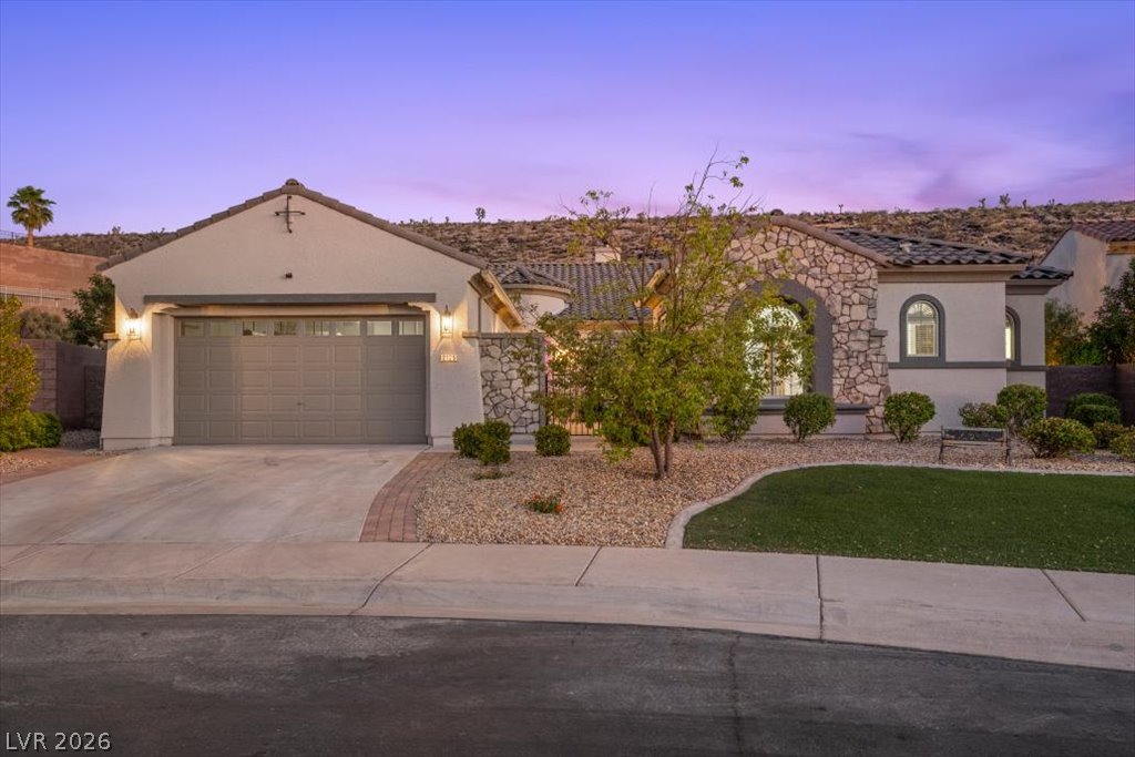 Stone accents and desert landscaping create a welcoming curb appeal under a vibrant twilight sky.