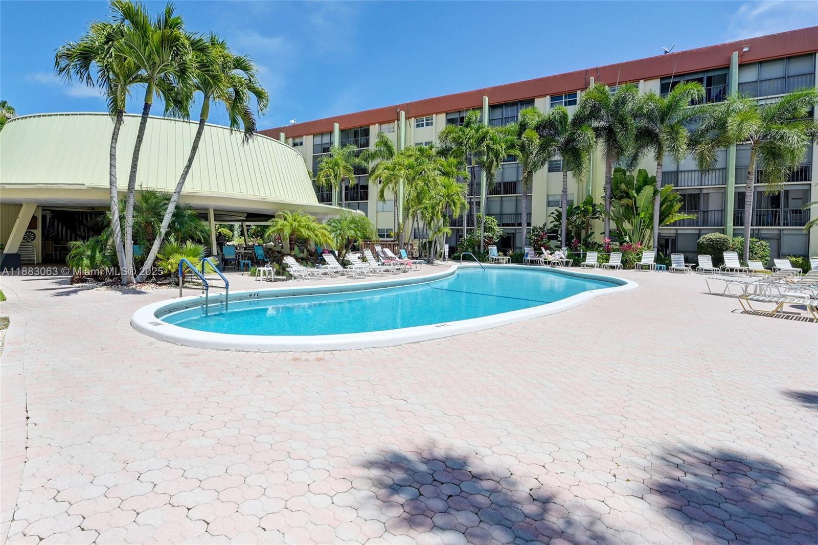 5321 Northeast 24th Terrace, Unit 112A Fort Lauderdale, FL 33308 - Photo 18 of 21 a view of a swimming pool with a table and chairs under an umbrella