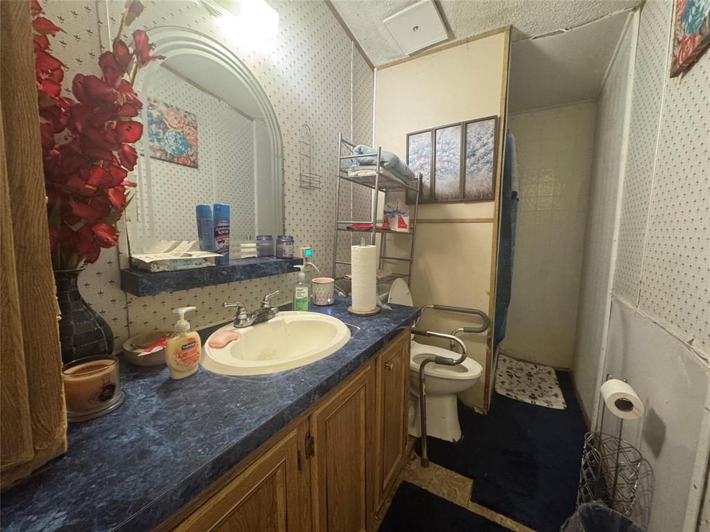1614 Cole Road Bellmead, TX 76705 - Photo 12 of 21 Bathroom vanity featuring a white oval sink with chrome faucet, blue patterned countertop, and wood-finish cabinetry