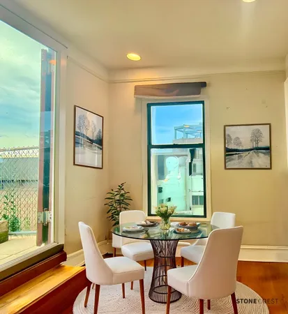 a view of a dining room with furniture a large window and wooden floor