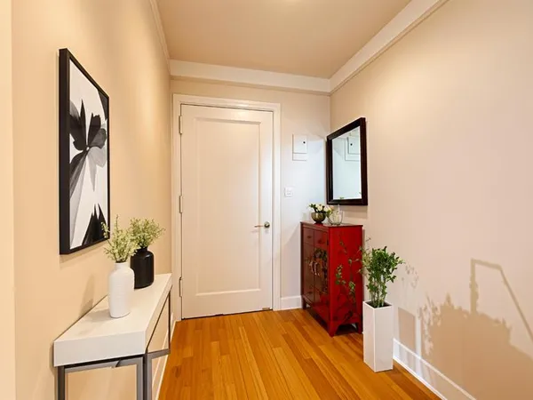 a view of a hallway with wooden floor and a bathroom