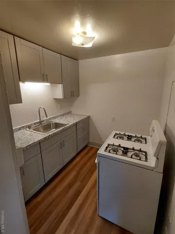 a kitchen with granite countertop a sink a stove and cabinets