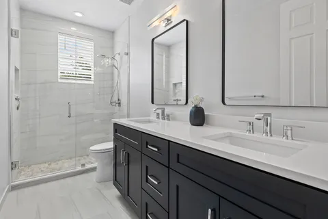 a bathroom with a double vanity sink toilet and shower