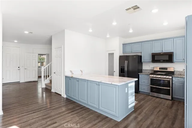 a kitchen with kitchen island granite countertop a refrigerator stove top oven and sink