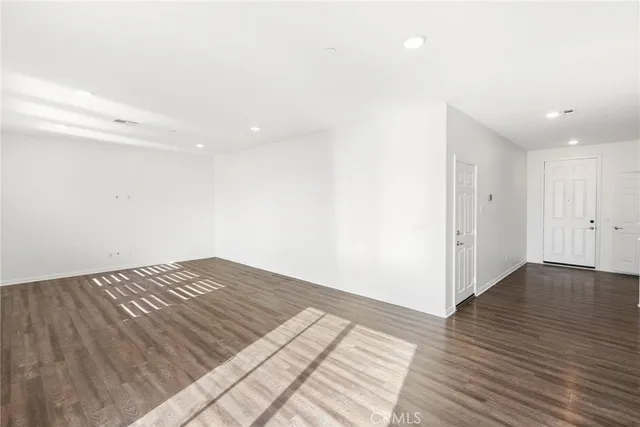 a view of a big room with wooden floor and a kitchen