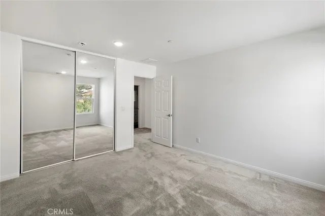 an empty room with windows and refrigerator