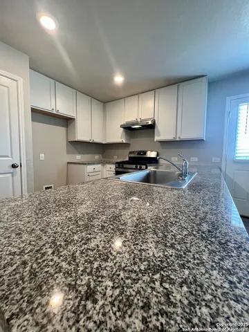 a kitchen with a sink a stove a refrigerator and cabinets