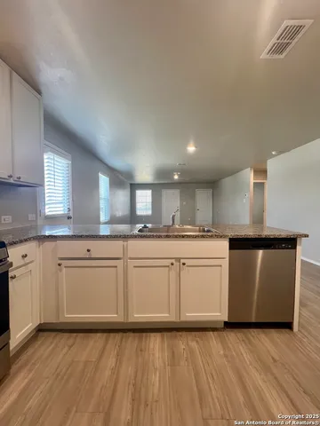 a kitchen with granite countertop a sink cabinets and wooden floor