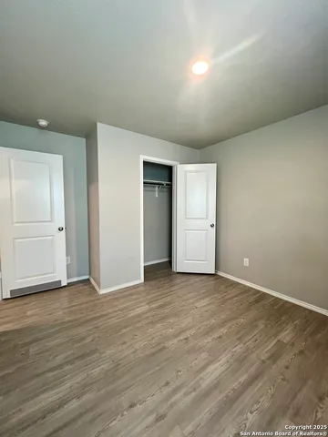 a view of an empty room with wooden floor and closet
