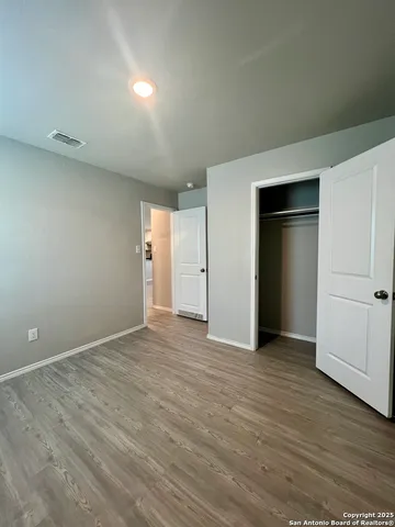 a view of an empty room with wooden floor and closet