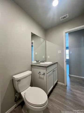 a bathroom with a granite countertop toilet a sink and a mirror