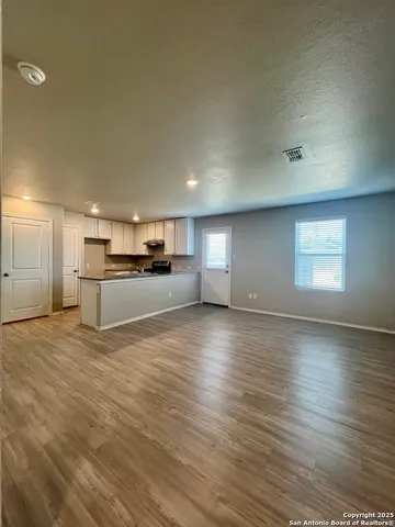 a view of kitchen and empty room with wooden floor