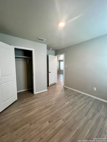 a view of an empty room with wooden floor and closet