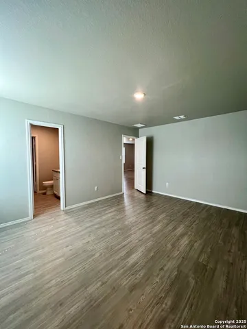 a view of an empty room with wooden floor and closet