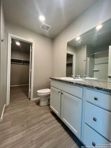 a bathroom with a granite countertop sink a toilet and mirror