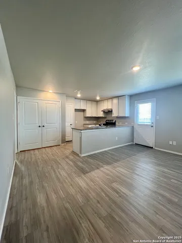 a view of kitchen and empty room with wooden floor
