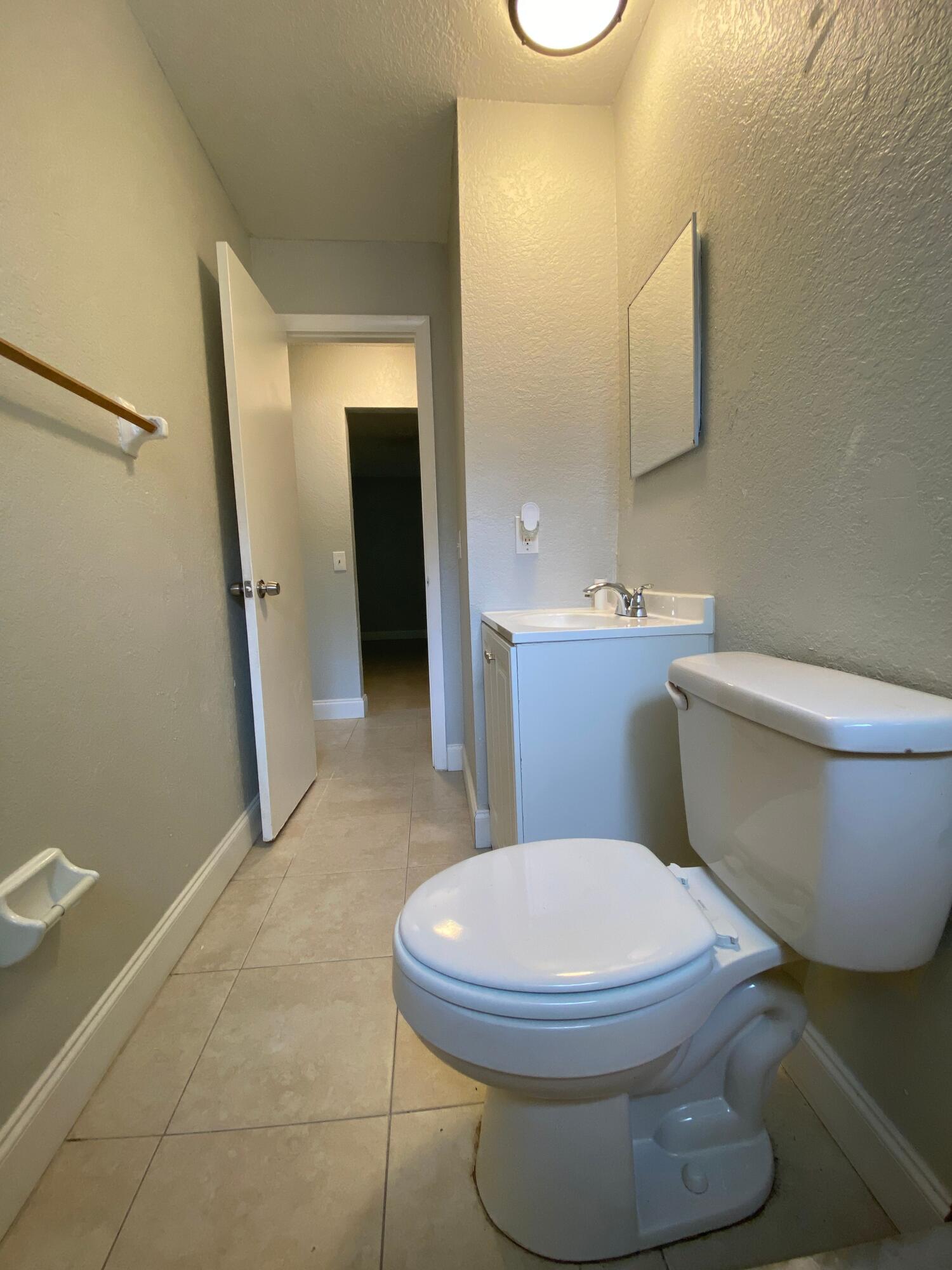 4327 Cocoanut Road West Palm Beach, FL 33406 - Photo 13 of 24 a white toilet sitting next to a bathroom sink and a mirror
