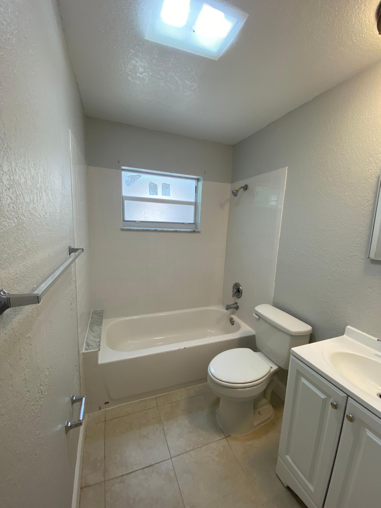 4327 Cocoanut Road West Palm Beach, FL 33406 - Photo 21 of 24 a bathroom with a granite countertop toilet a sink and a bathtub