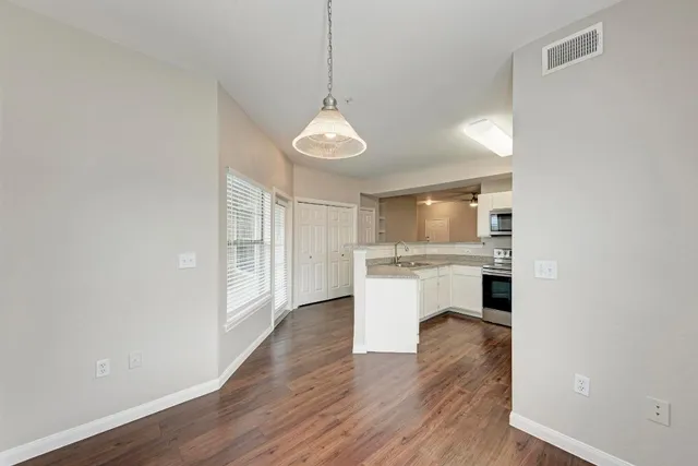 a dining room with wooden floor a chandelier a glass table and chairs