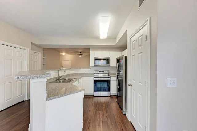 a kitchen with stainless steel appliances granite countertop a stove top oven a refrigerator a sink with wooden floor