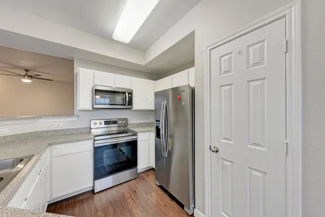 a kitchen with cabinets stainless steel appliances and wooden floor