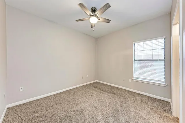 an empty room with a window and a fan