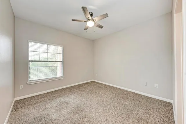 an empty room with ceiling fan and window
