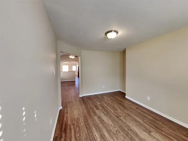 an empty room with wooden floor and mirror