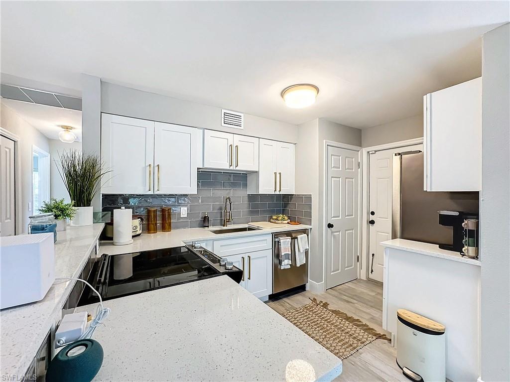 9 Knights Bridge Road, Unit 30 Naples, FL 34112 - Photo 23 of 47 a kitchen with a sink a stove and white cabinets