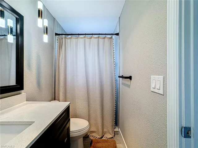 a bathroom with a sink a toilet a mirror and shower curtain