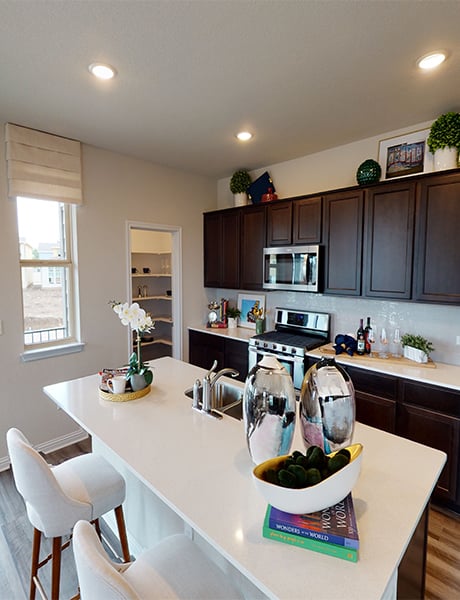 8111 Springsteen Drive Austin, TX 78744 - Photo 4 of 11 Representative Image - Kitchen featuring light wood-type flooring, dark wood finish cabinetry, stainless steel appliances, a kitchen breakfast bar, and a kitchen island with sink