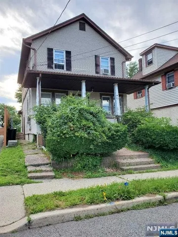 a view of a house with a yard plants and large tree