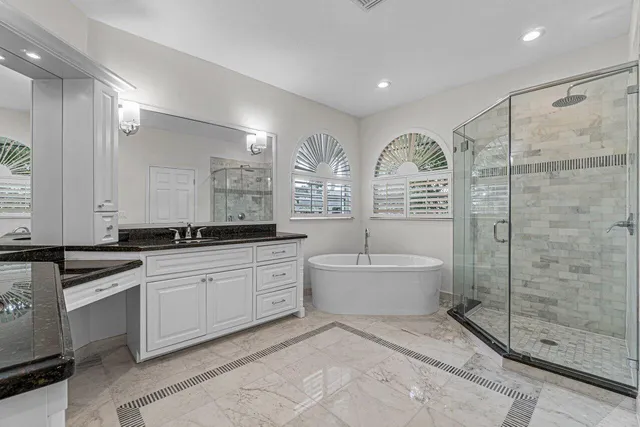 a large bathroom with a granite countertop tub sink a mirror and a shower