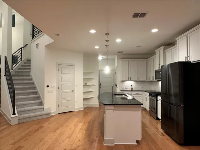 a kitchen with granite countertop a refrigerator stove and cabinets