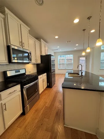 a kitchen with stainless steel appliances kitchen island granite countertop a sink a stove top oven a counter space and cabinets