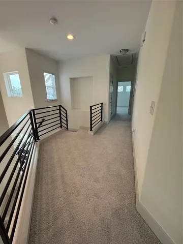 a view of an empty room with wooden floor and windows