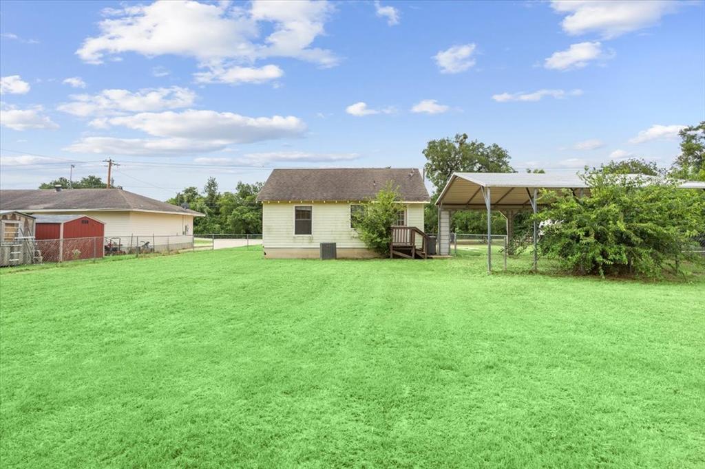608 9th Street Hico, TX 76457 - Photo 17 of 23 Expansive green lawn with a white single-story residence featuring a dark roof and exterior steps