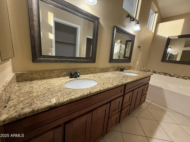 a bathroom with a granite countertop sink a mirror and a bathtub