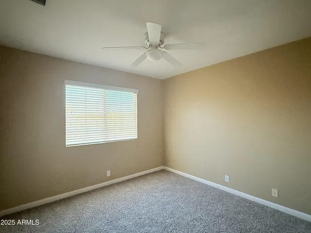 an empty room with a window and a fan