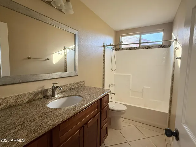 a bathroom with a granite countertop sink toilet mirror and shower